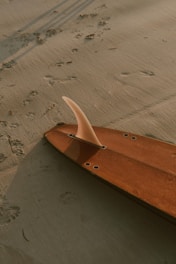 A beginner surfboard with a smooth finish on the sand.