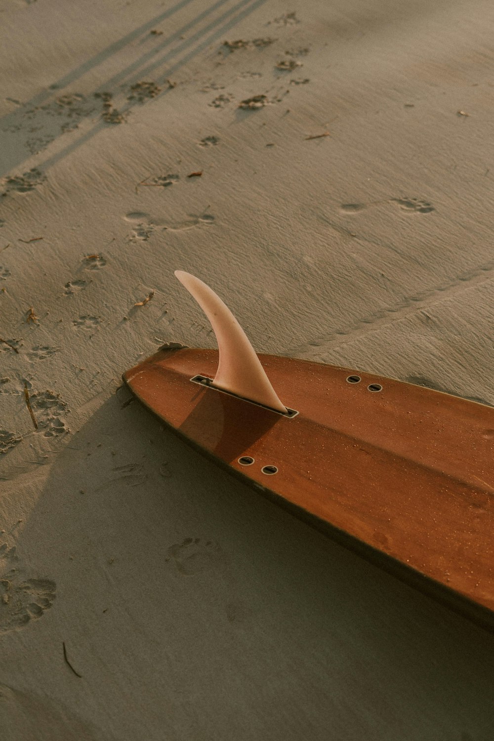 a wooden surfboard laying on the sand at the beach