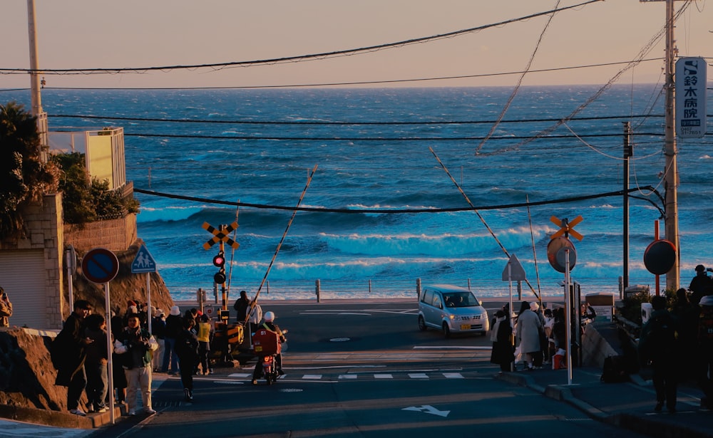 a group of people walking down a street next to the ocean