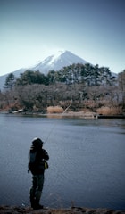 Outdoor scene showing a person wearing a paracord bracelet while fishing by a lake.