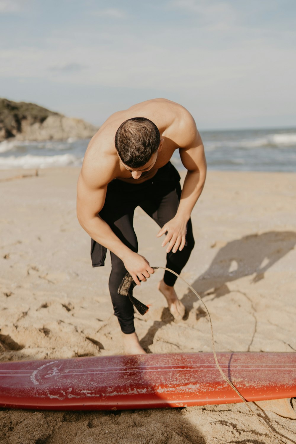 a man standing on a beach next to a surfboard