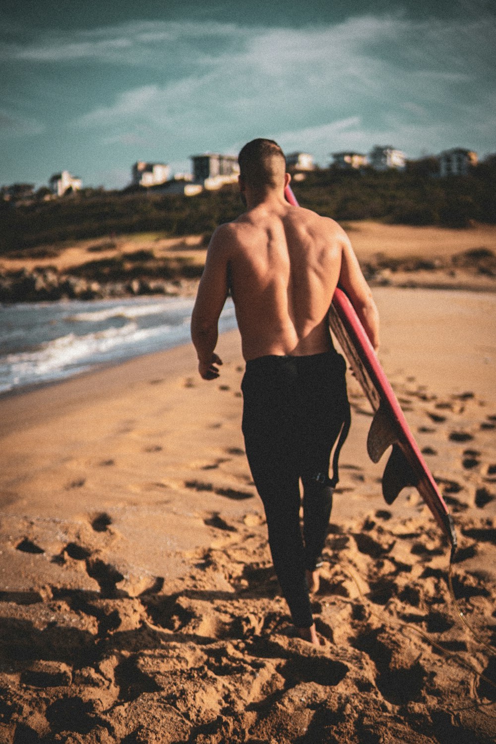 a man walking on the beach with a surfboard