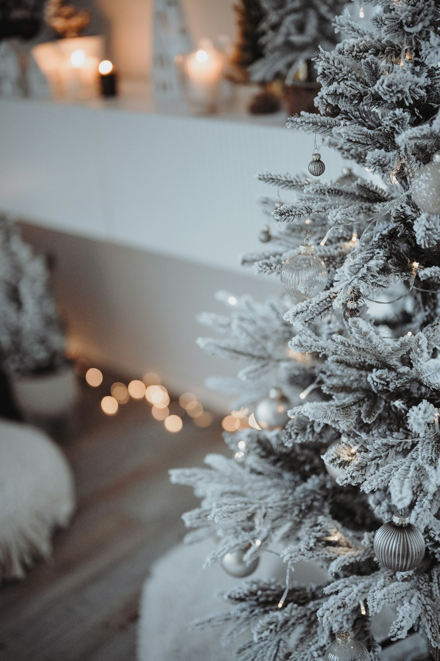 Pale ornaments and small warm lights on a decorated Christmas tree.
