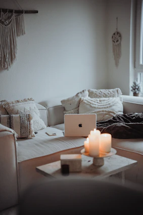 Boho macrame wall art hanging above a minimalist sofa with warm lighting