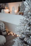 a white christmas tree in front of a fireplace