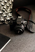 A student writing notes in a photography log book beside a DSLR camera
