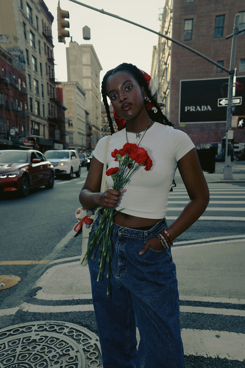 a woman standing on the side of a street holding flowers