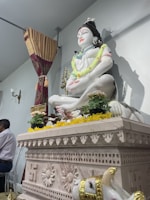 A serene marble religious idol placed in a softly lit temple corner, showcasing delicate carving.