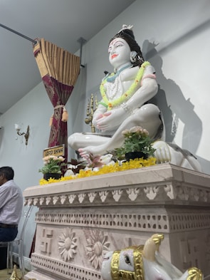 A serene marble religious idol placed in a softly lit temple corner, showcasing delicate carving.