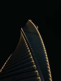 A sleek, dark-toned architectural model of a towering futuristic skyscraper glowing softly against a night sky.