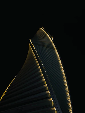 A sleek skyscraper with vertical lines glowing under a twilight sky, symbolizing modern luxury.