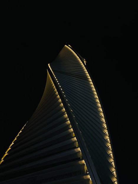 A sleek, dark-toned architectural model of a towering futuristic skyscraper glowing softly against a night sky.