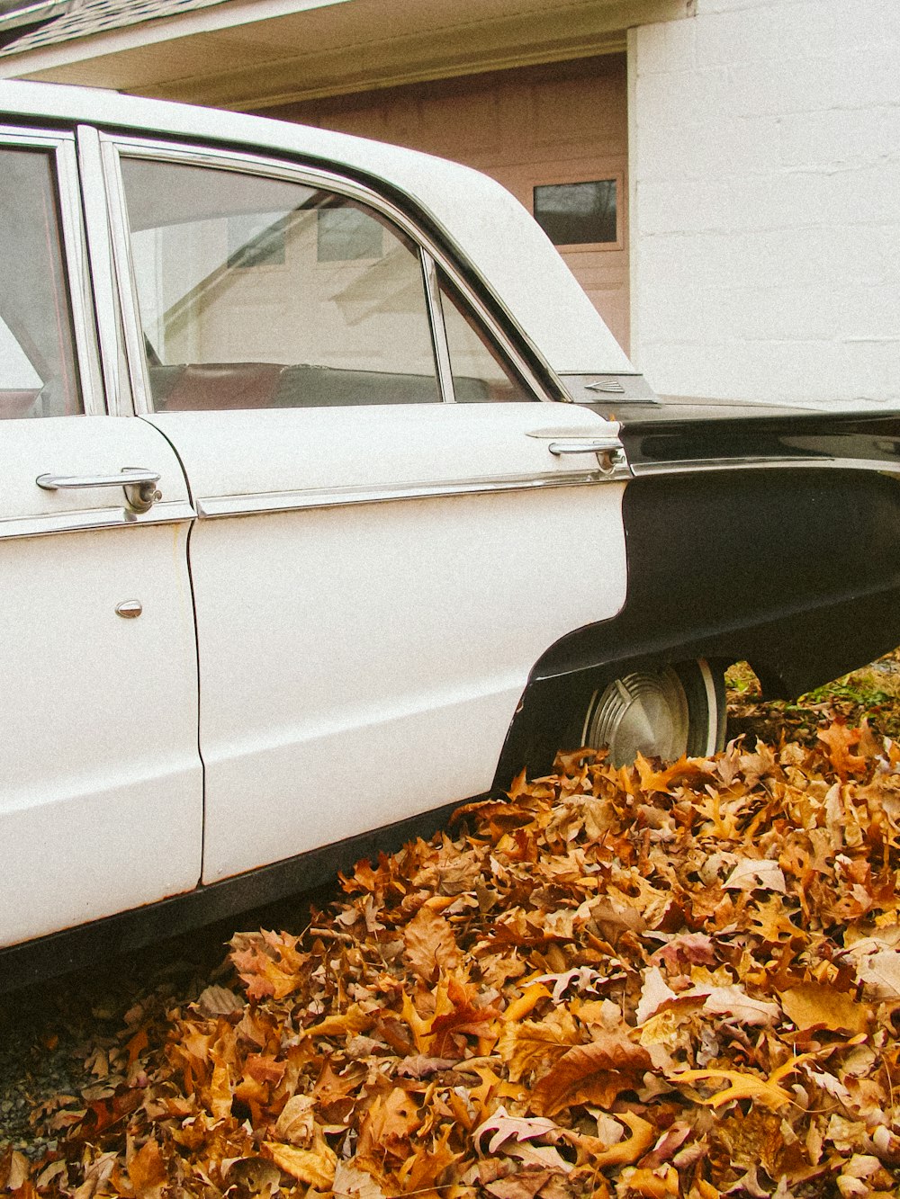 a white car parked next to a pile of leaves