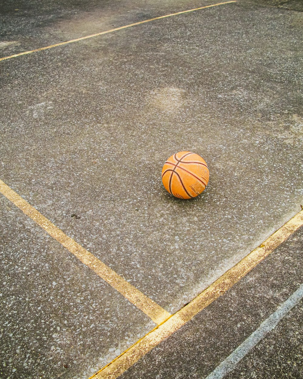a basketball sitting on the ground in a parking lot