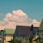 A serene view of a residential plot with lush greenery and clear blue skies.