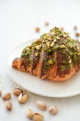 a white plate topped with a pastry covered in toppings