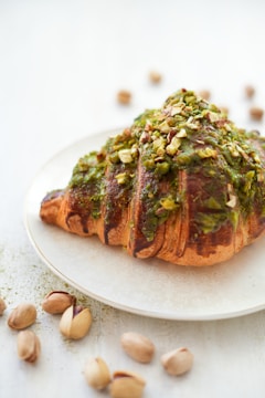 a white plate topped with a pastry covered in toppings