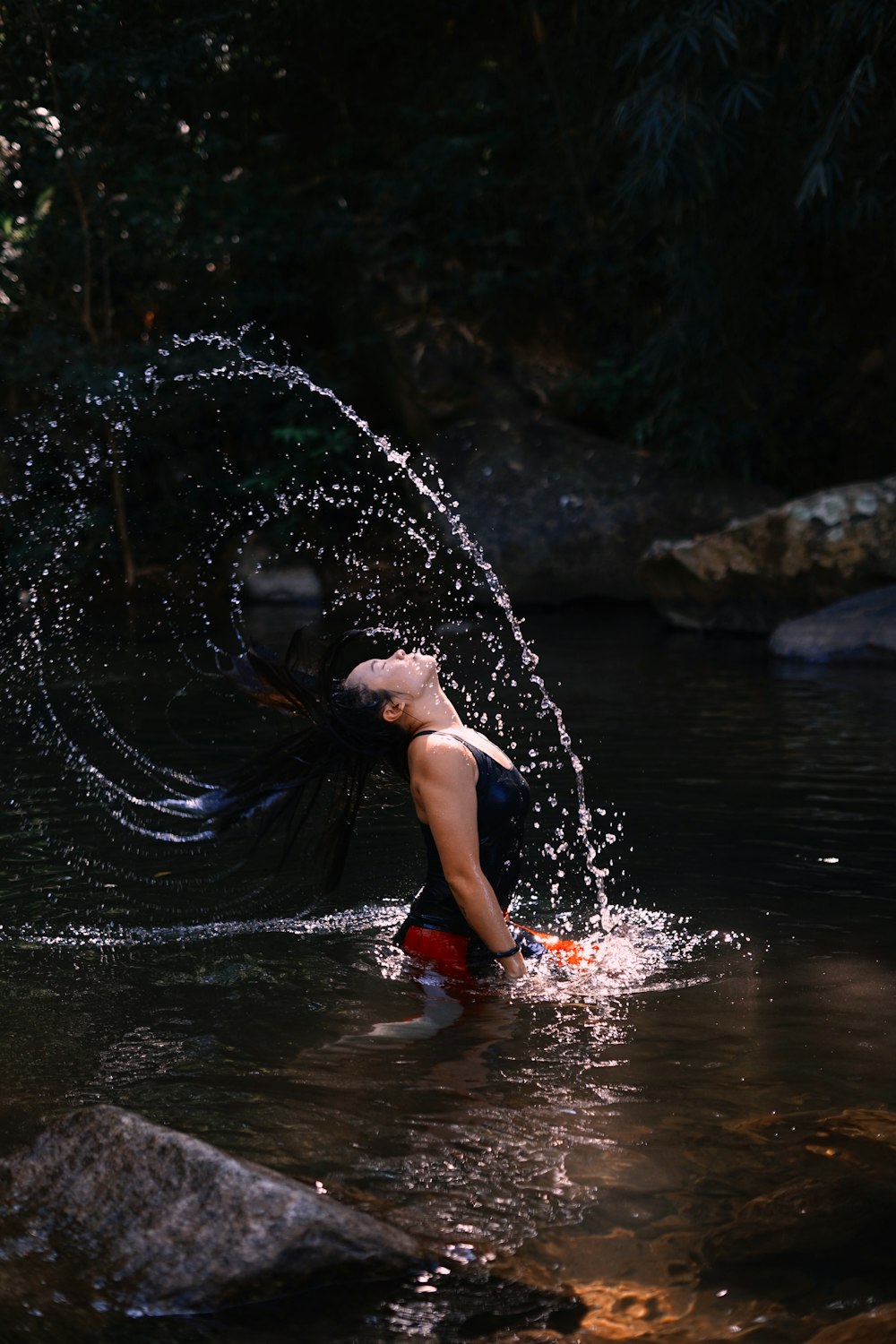 a woman in a body of water spraying water on her head