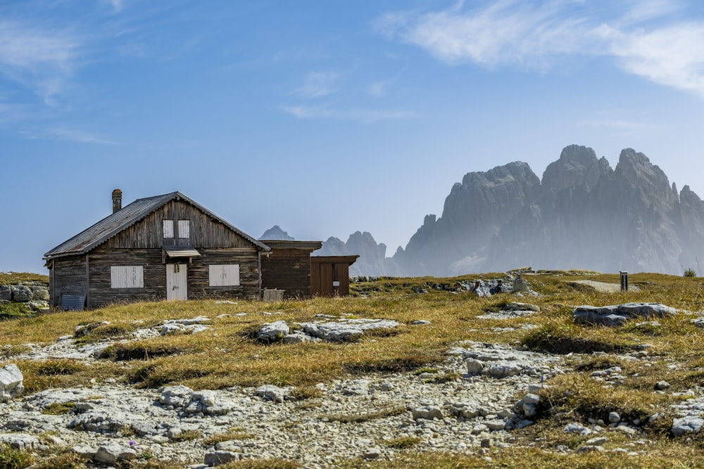 a small cabin in a field with mountains in the background