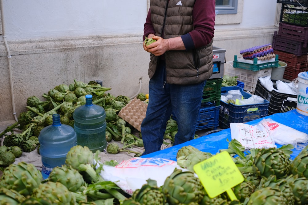 a man standing in front of a pile of vegetables