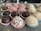 An assortment of round, chocolate-colored treats placed in colorful, decorative paper cups on a speckled gray tray. The sweets vary in texture, some dusted with cocoa or covered in shredded coconut and other ingredients.