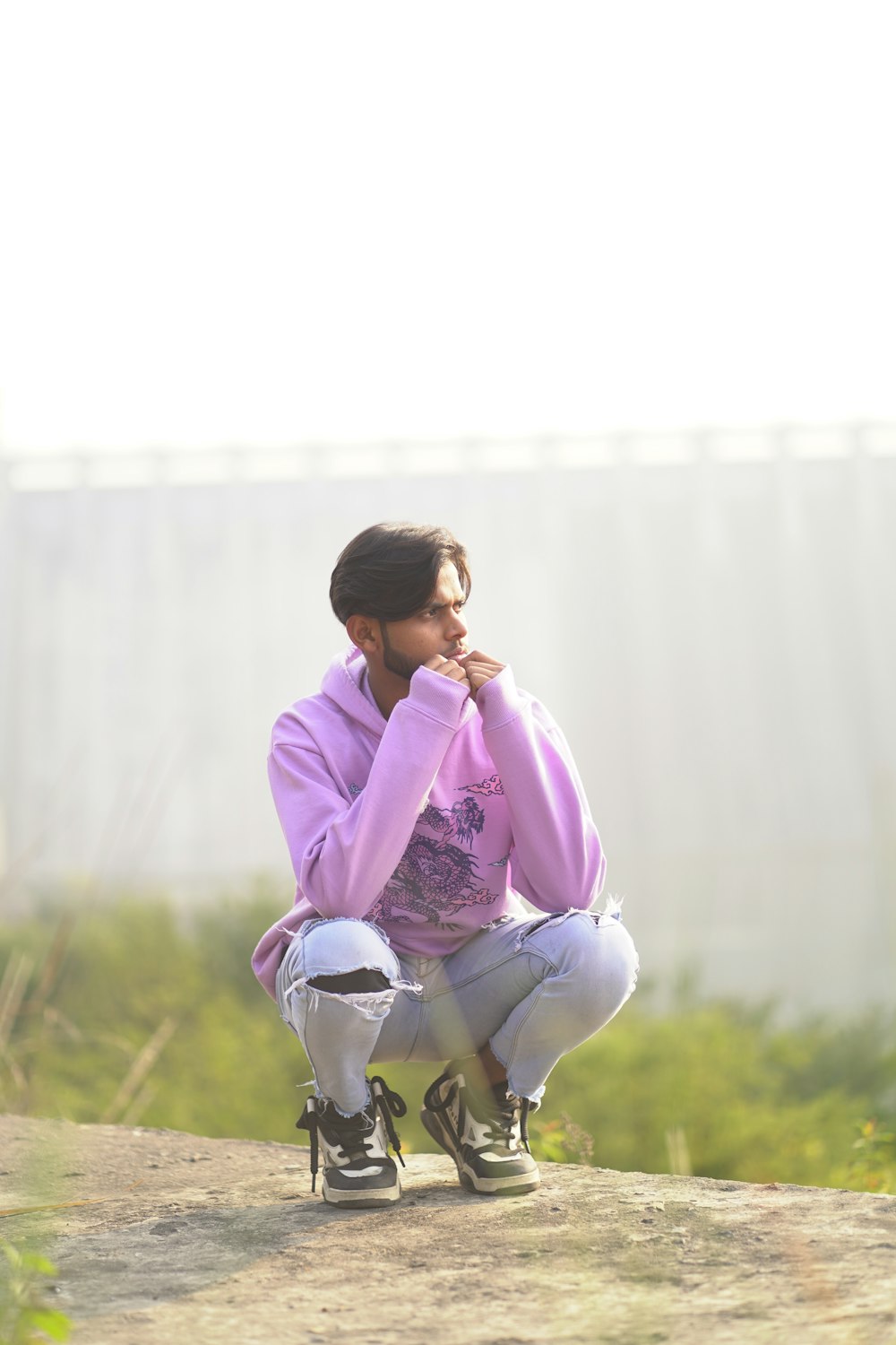 a man sitting on a skateboard on a dirt road