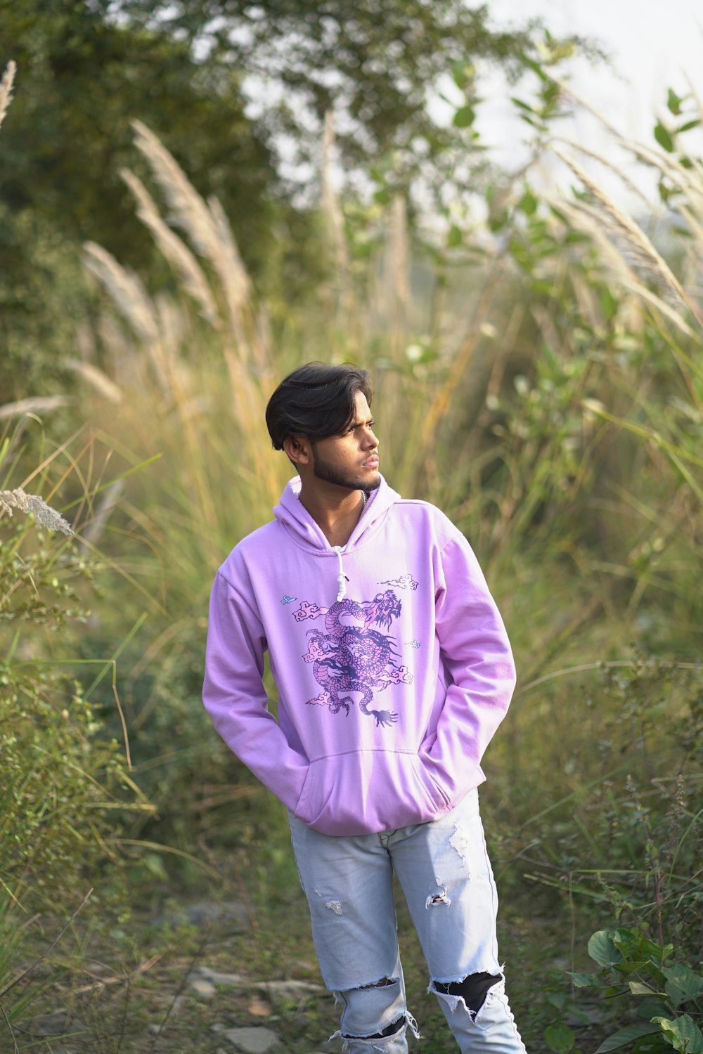 a man in a purple hoodie standing in a field