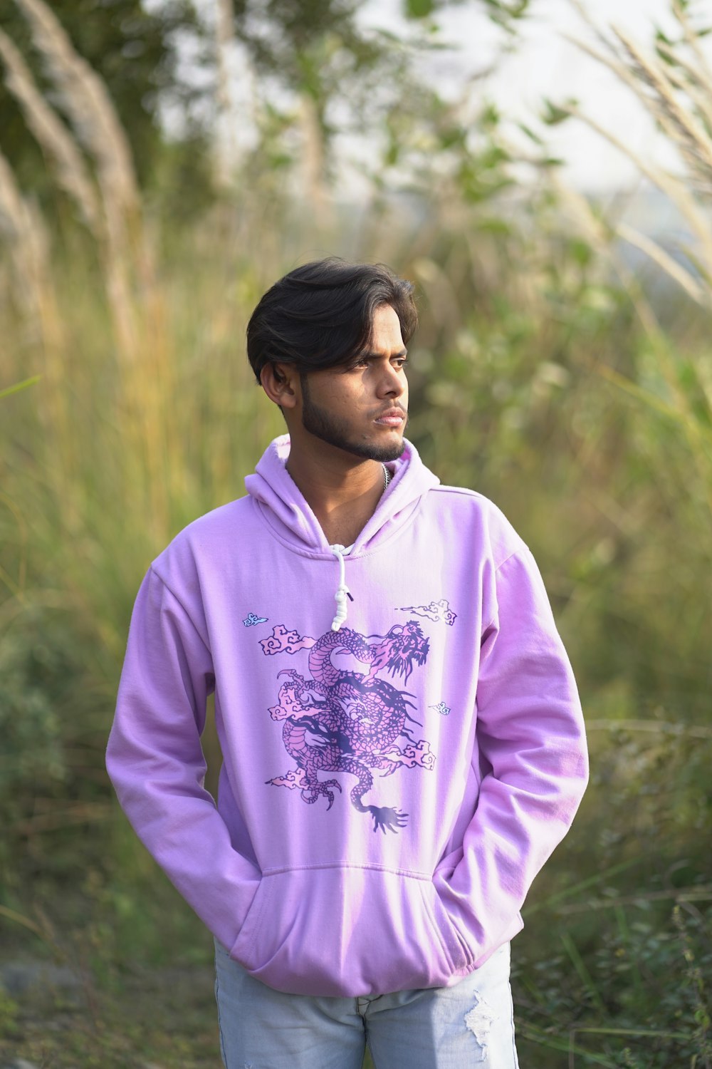 a man in a purple hoodie standing in a field