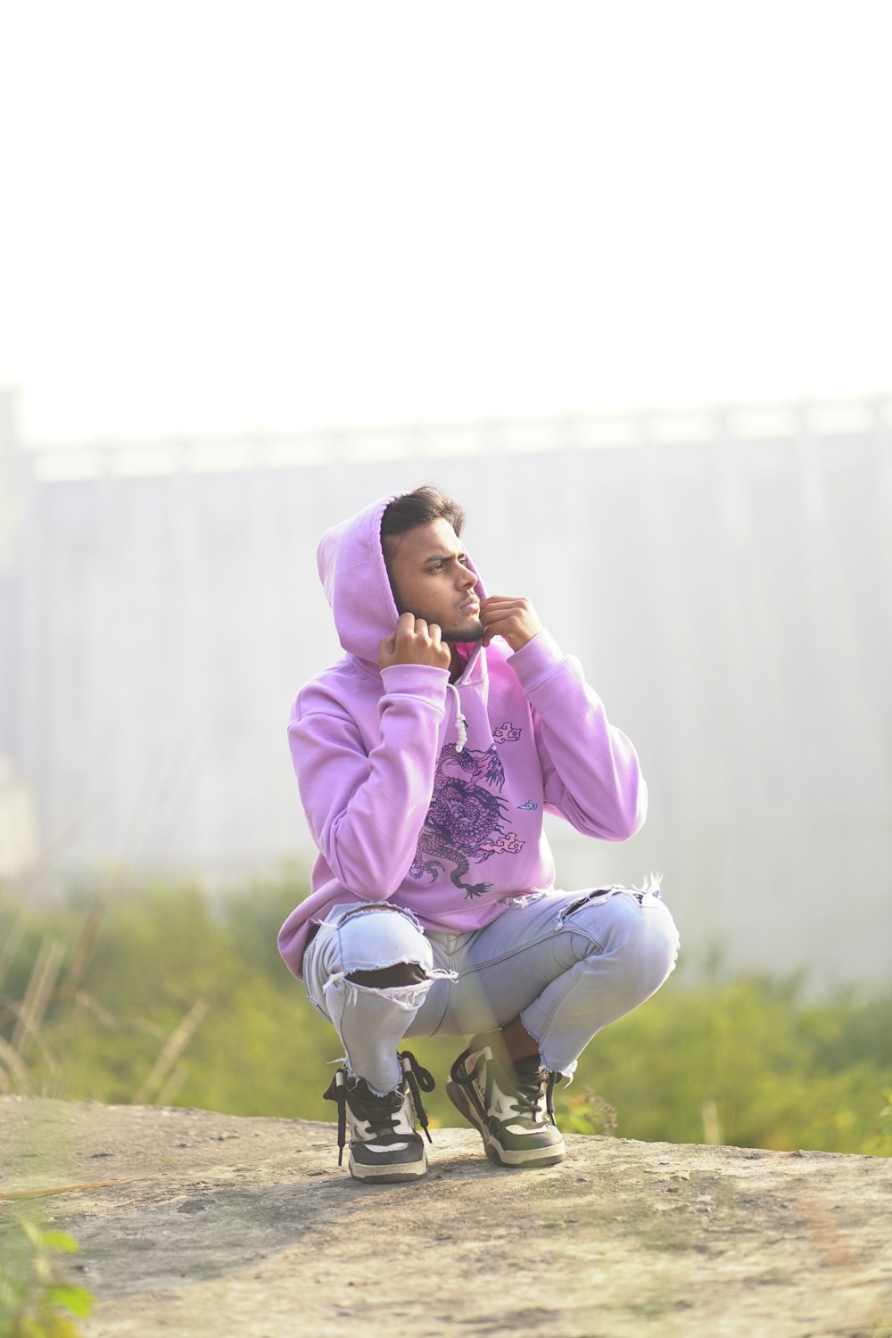 a man in a purple hoodie sitting on a skateboard
