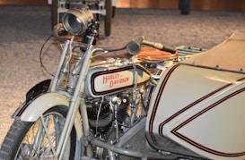 A vintage Harley-Davidson motorcycle with a sidecar is prominently displayed. The motorcycle features classic design elements like a large headlamp, spoked wheels, and a fuel tank with the iconic Harley-Davidson logo. The sidecar is color-coordinated with the motorcycle, enhancing its antique aesthetic.
