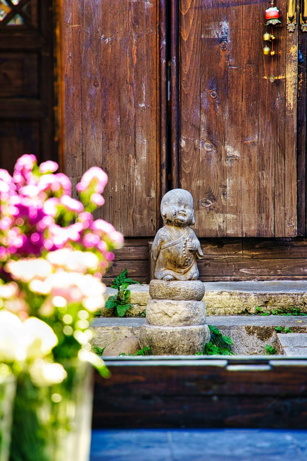 Uma pequena estátua de Buda sentada em frente a uma porta de madeira