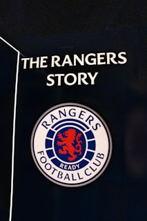 A sign featuring the words 'The Rangers Story' above a round emblem with a red lion and the words 'Rangers Football Club.'