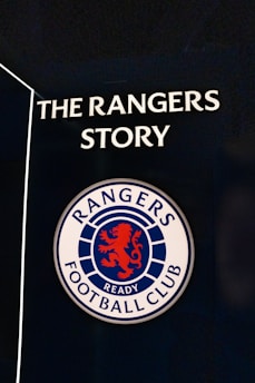 A sign featuring the words 'The Rangers Story' above a round emblem with a red lion and the words 'Rangers Football Club.'