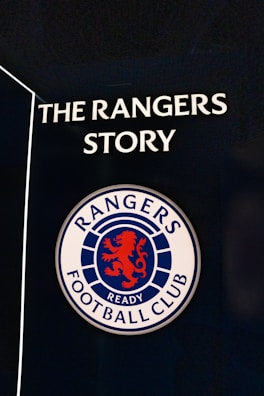 A sign featuring the words 'The Rangers Story' above a round emblem with a red lion and the words 'Rangers Football Club.'