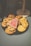 A variety of cookies are arranged on a dark platter. The assortment includes chocolate chip cookies, cookies with white chocolate chunks, and a distinct pink cookie shaped like a tree with white icing decoration.