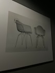 Two chairs with modern, minimalist design featuring transparent seats and metal legs are displayed against a neutral backdrop.