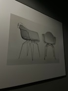 Two chairs with modern, minimalist design featuring transparent seats and metal legs are displayed against a neutral backdrop.