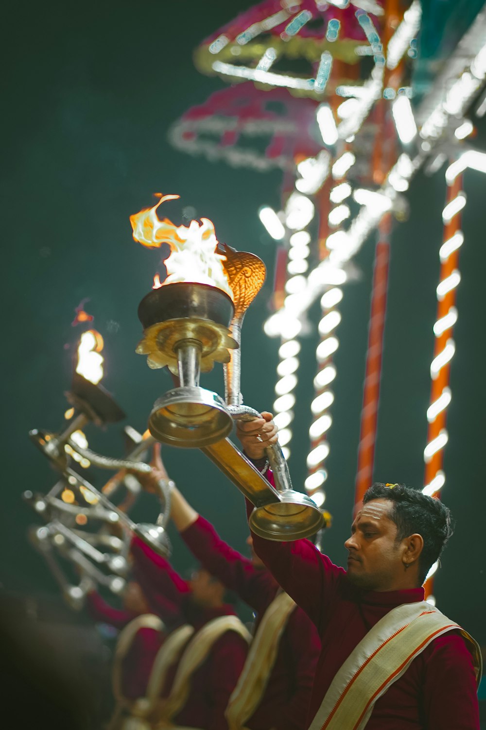 a man holding a lit candle in front of a carnival ride