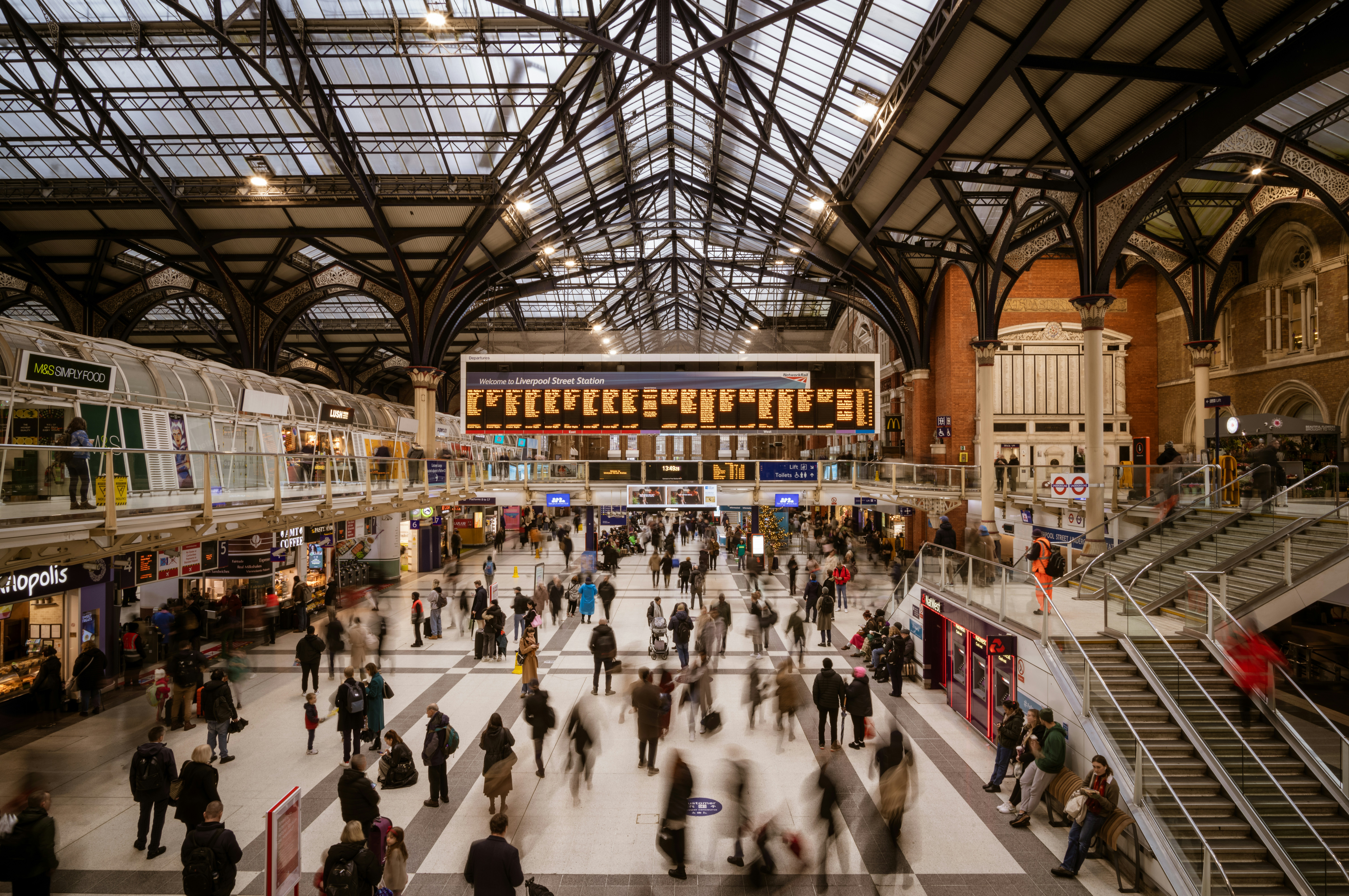 a crowd of people walking around a train station