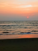 A breathtaking sunset over a tranquil beach with gentle waves lapping the shore.