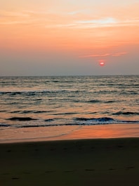 A tranquil beach scene with clear waters and gentle waves at sunset.
