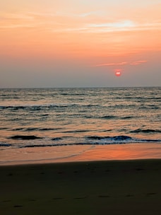 A tranquil beach scene with clear waters and gentle waves at sunset.