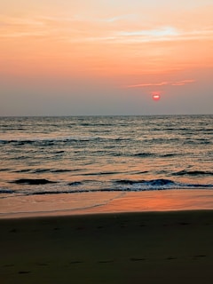 A tranquil beach at sunset with gentle waves lapping the shore.