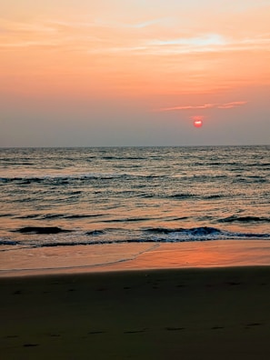 A breathtaking sunset over a tranquil beach with gentle waves lapping the shore.