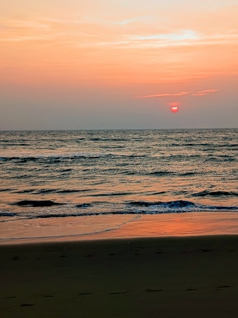 A tranquil beach scene with gentle waves and a sunset.