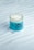 A jar of hair mask with a creamy white substance is displayed on a textured surface. The packaging features a blue label with the brand name 'VITA COCO' and illustrated green leaves.