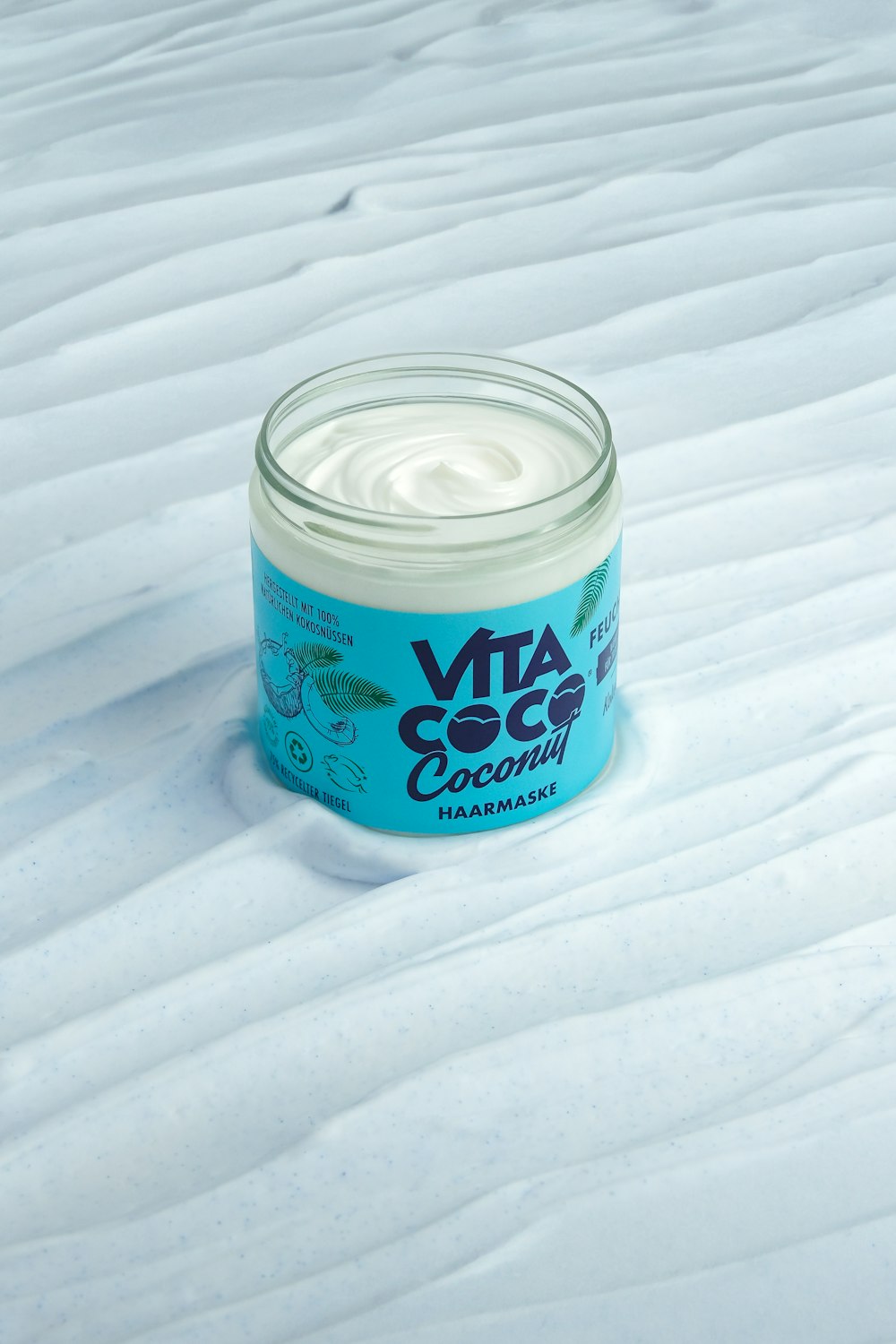 a jar of cream sitting on top of a snow covered ground