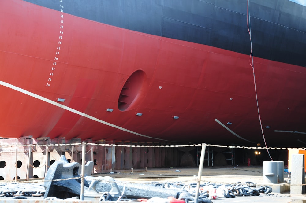 a large red and black boat being worked on