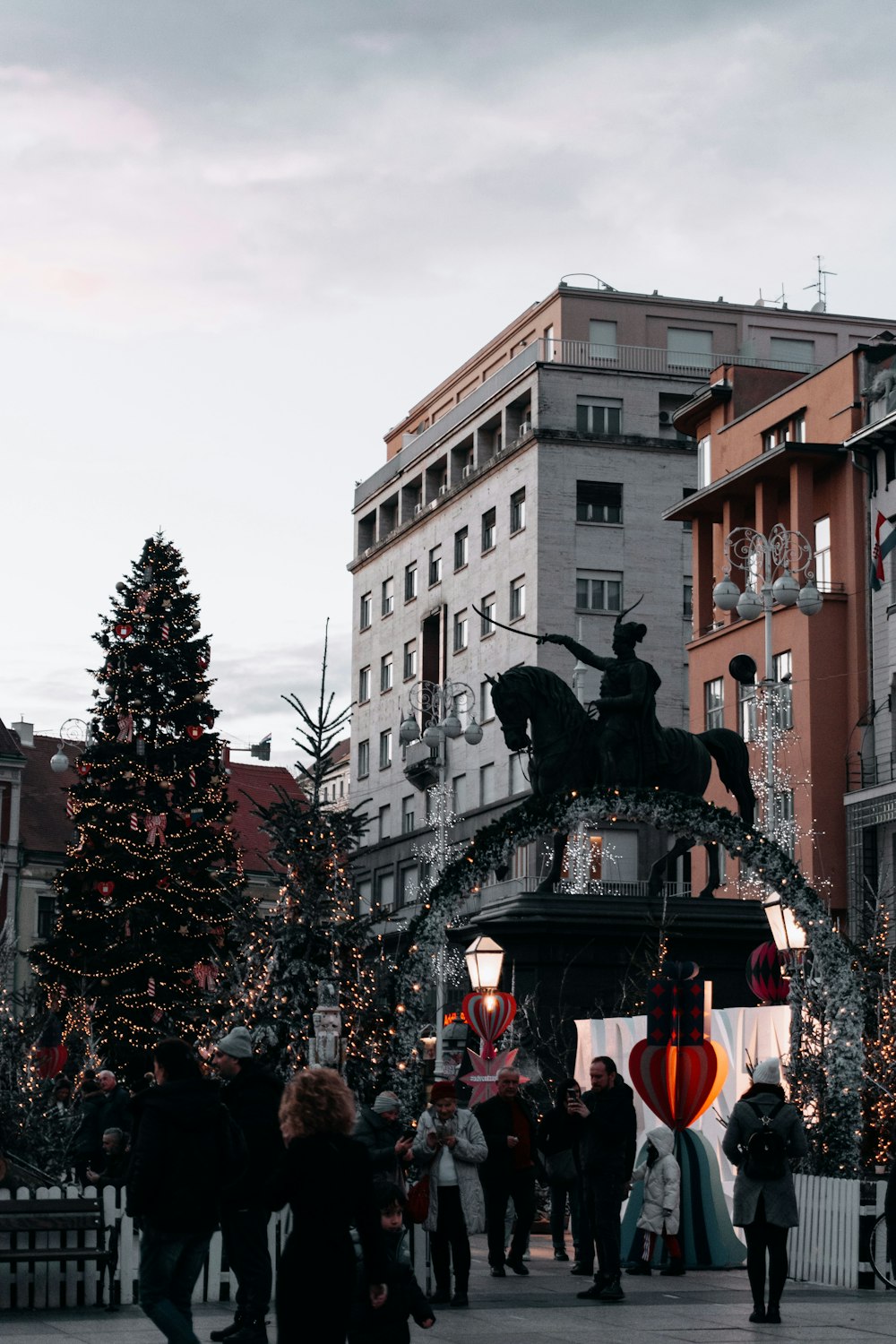 a crowd of people walking around a christmas tree