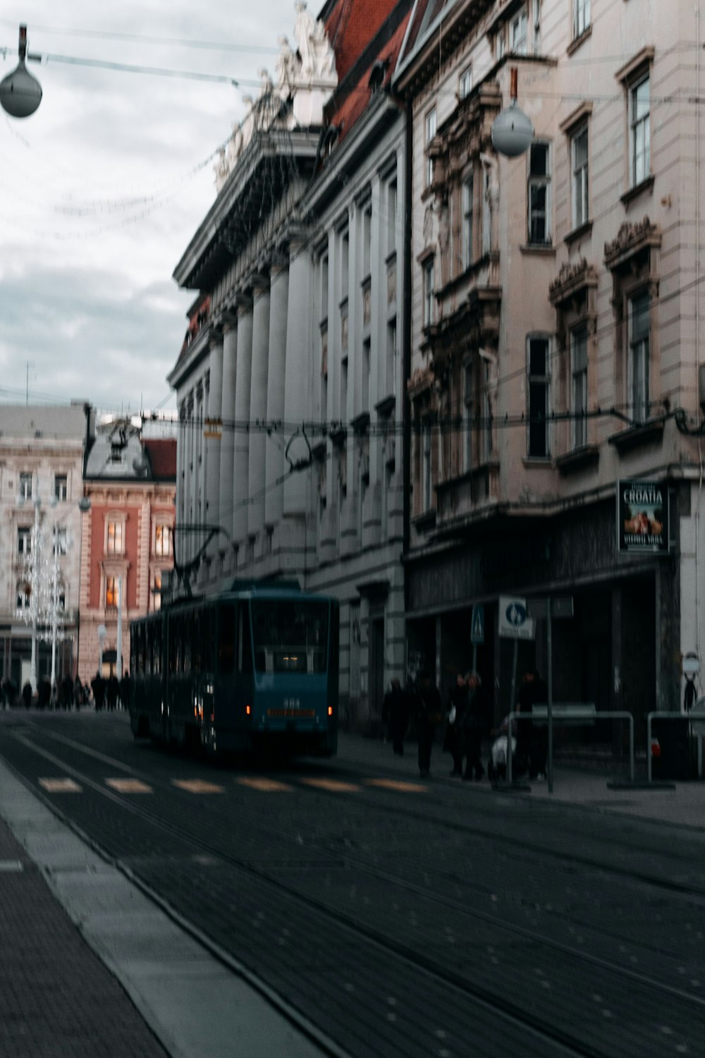 a blue bus driving down a street next to tall buildings